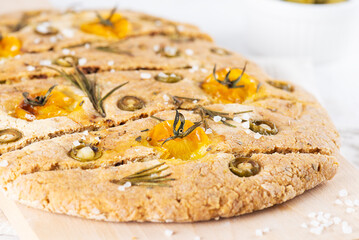 Sliced focaccia with olives, tomatoes, rosemary and spices on the table. Sugar, gluten and lactose...