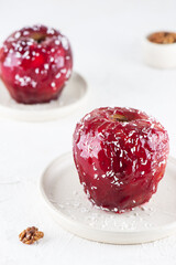 Red apple dessert with walnut filling, syrup and coconut flakes on the table. Healthy food, sugar, gluten and lactose free, vegan.