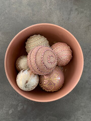 Top view of Christmas Balls in dusty rose and champagne gold color tones photographed in a dusty rose coloured ceramic bowl placed on a concrete grey back ground 
