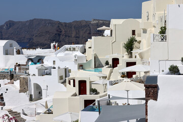 Fototapeta na wymiar Whitewashed houses with terraces and pools and a beautiful view in Oia on Santorini island, Greece