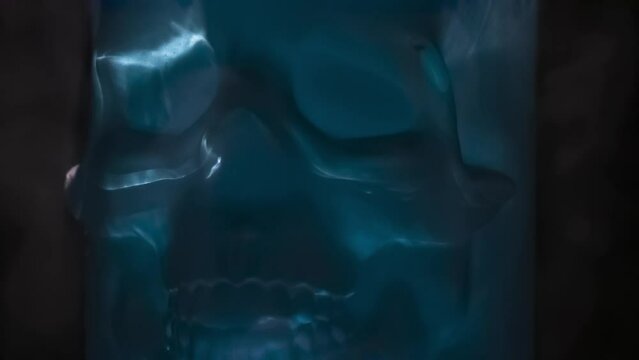 Matte Blue Skull. Frosted blue glass skull rotates slowly in icy vapors against black background