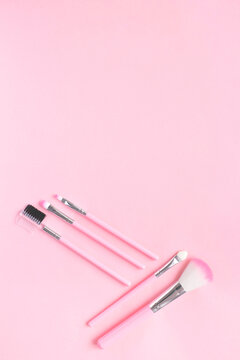 Cute makeup brushes on a pink background. Vertical photo. The concept of an advertising picture for a make-up artist's blog. Vertical photo. copy space, flat lay, top view