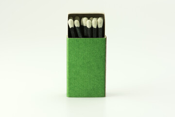 black match sticks with white tips, in a green match box, isolated on natural white background....