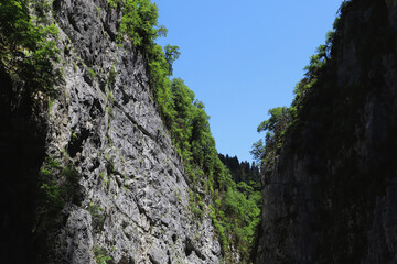 Abkhazia.May 27, 2021.Enchanting view of mountains and blue sky.Huge rocks staying in front of each other covered by forest.
