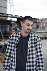 Portrait of man with mustache in checkered black and white shirt outside.