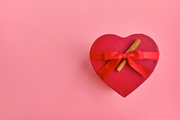 Gift red box in the shape of a heart with a ribbon on a pink background. View from above. Place for text. Valentine's Day. The 14th of February