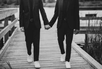 European Gay Couple holding hands, wearing black suits, wedding day of a same sex couple. Black and white art photography.