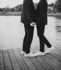 European Gay Couple holding hands, wearing black suits, wedding day of a same sex couple. Black and white art photography.