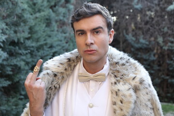 Eccentric looking wealthy man showing middle finger