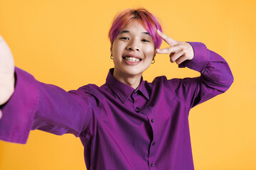 Asian boy showing peace gesture while taking selfie photo