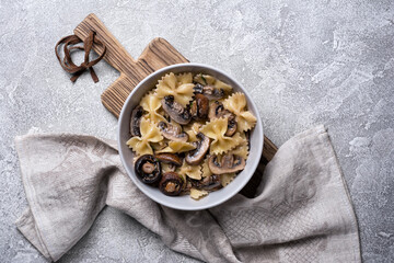 Fototapeta na wymiar Bowl of italian farfalle pasta and mushrooms with cream sauce