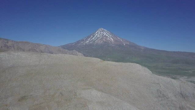 A beautiful Drone flight moving up showing Damavand mountain in Iran and a blue sky
