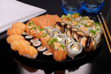 Japanese food combo of sushis and sahimis in black background