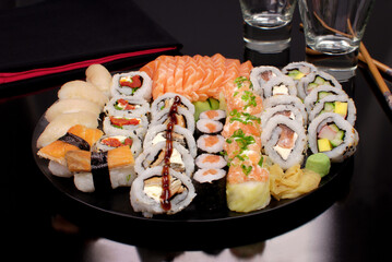 Japanese food combo of sushis and sahimis in black background