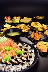 Japanese food combo of sushis and sahimis in black background
