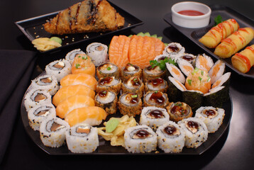 Japanese food combo of sushis and sahimis in black background