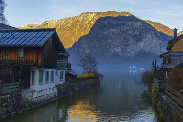 Fototapeta na wymiar Old traditional Austrian houses on a mountain lake shore on winter sunset