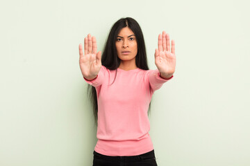 hispanic pretty woman looking serious, unhappy, angry and displeased forbidding entry or saying...