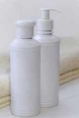 Set of white cosmetic bottles mockup with a towel and a natural soap on a white table. Hygiene and healthy life concept. Close up, selective focus