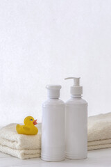 Fototapeta na wymiar Set of white cosmetic bottles mockup with a towel and a natural soap on a white table. Hygiene and healthy life concept. Close up, selective focus
