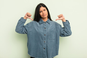 hispanic pretty woman looking sad, disappointed or angry, showing thumbs down in disagreement,...