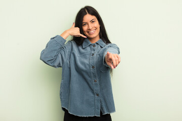 hispanic pretty woman smiling cheerfully and pointing to camera while making a call you later...