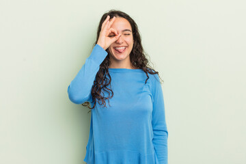 hispanic pretty woman smiling happily with funny face, joking and looking through peephole, spying...