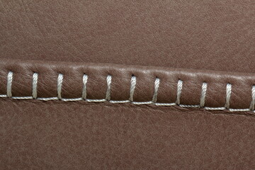 Decorative seam made of white thread on genuine leather