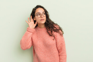 hispanic pretty woman looking serious and curious, listening, trying to hear a secret conversation...