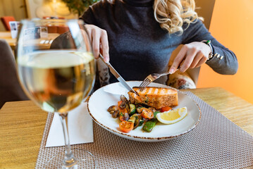 woman eating salmon steak with roasted vegetables