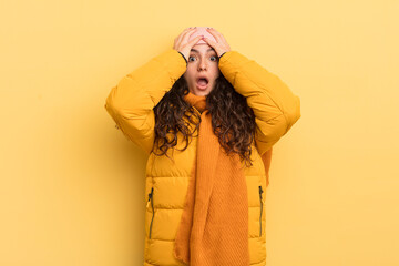 hispanic pretty woman feeling horrified and shocked, raising hands to head and panicking at a...