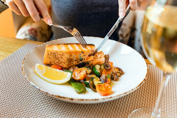 woman eating salmon steak with roasted vegetables
