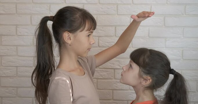 Measuring height in childhood. A playful children measure her height in the room.
