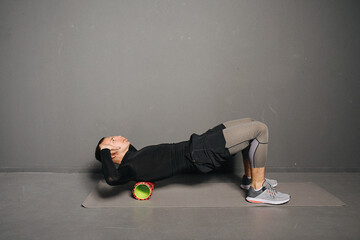 Athletic young man doing fitness with foam roller