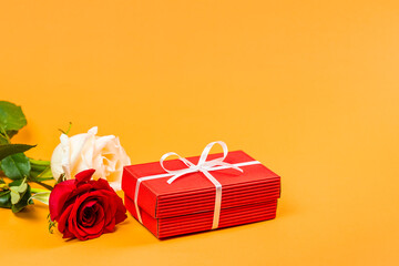 Red gift box with a white ribbon and roses