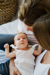 Young mom and dad are holding a newborn in their arms. The family holds a newborn baby girl in their arms.