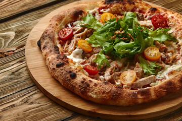 Pizza Caesar. Pizza with chicken, tomato, cheese and lettuce on wooden board. Top view. Free space for your text. Delivery food
