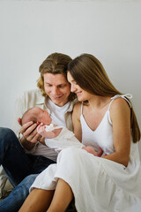 Young mom and dad are holding a newborn in their arms. The family holds a newborn baby girl in their arms.