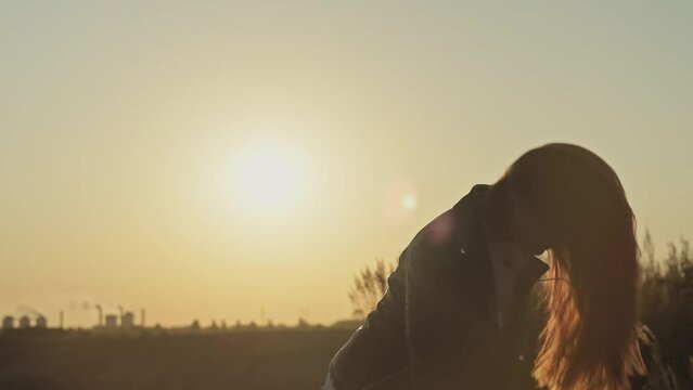 Young woman waves her hair at sunset sky background. Sunbeams. Freedom concept. Female enjoying nature in slow motion