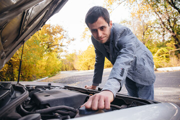A man looks under the quota of a broken car.