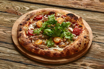Pizza Caesar. Pizza with chicken, tomato, cheese and lettuce on wooden board. Top view. Free space for your text. Delivery food