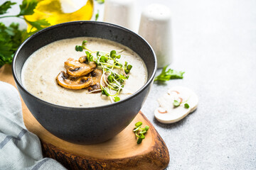 Mushroom Soup in black bowl on light stone table.