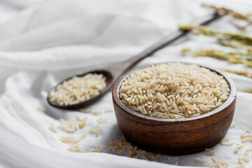 The grain in a wooden cup rests on a white cloth, healthy food and diet concept.