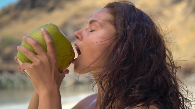 Portrait of charming dark haired young woman drinking coconut water on the tropical beach