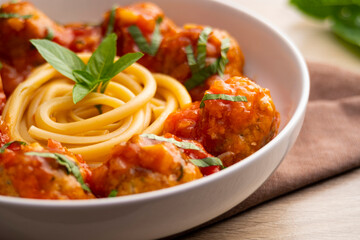 Long Spaghetti with meatballs in tomato sauce in a white plate on wooden table.Selective focus
