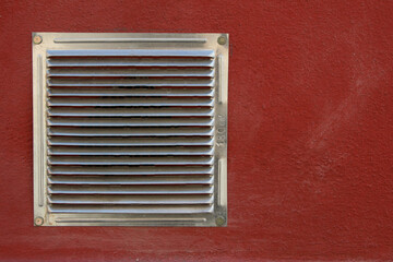 metal vent isolated on a grainy wall on a maroon wall