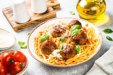 Pasta with beef Meatballs in tomato sauce, basil and parmesan on light stone table. Italian food.