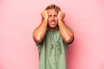 Young caucasian man isolated on pink background crying, unhappy with something, agony and confusion...