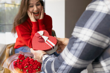 Valentine's Day concept. Happy man and woman in love presenting gifts to each other at a cafe. A young loving couple celebrating Valentine's Day in the restaurant.