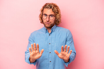 Young caucasian man isolated on pink background rejecting someone showing a gesture of disgust.